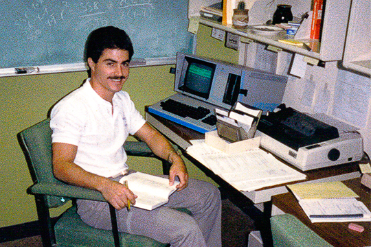 A young Len Jessup sits at desk with computer