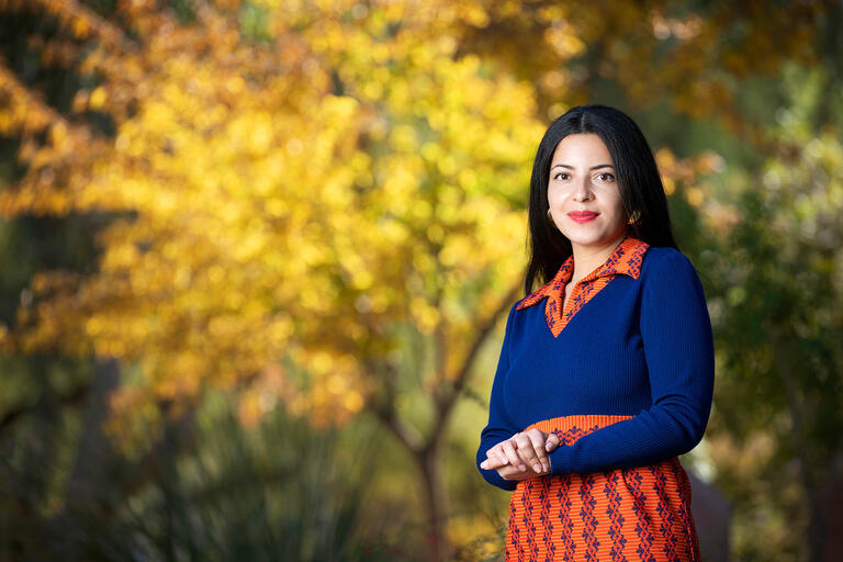 Sara Ortiz, program manager for the Black Mountain Institute. She manages events, readings, etc. for the fellows and writers-in-residence, poses in front of trees on campus.